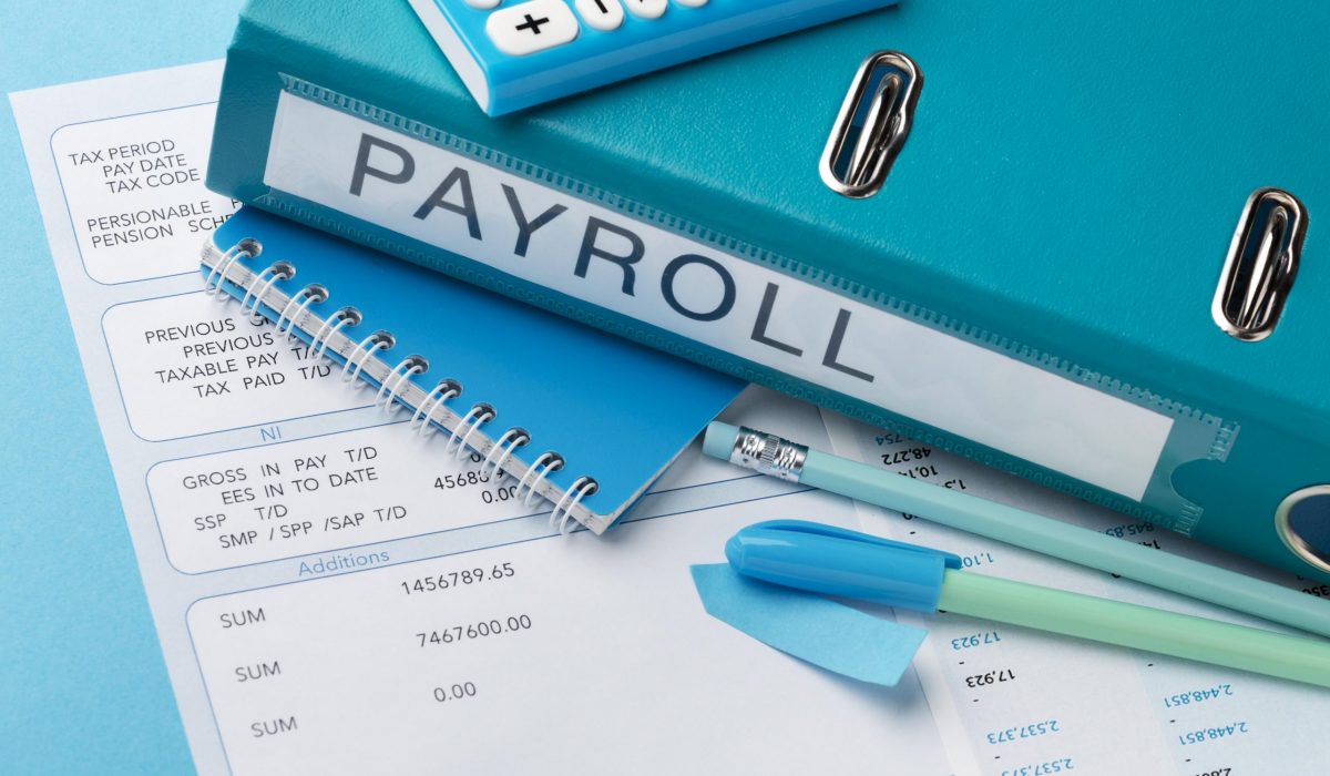Benefits of Outsourcing Payroll for SMEs in Malaysia – Payroll documents, calculator, and blue binder labeled ‘PAYROLL’ highlighting cost savings, efficiency, and compliance improvements for small businesses. Payroll documents, calculator, and blue binder labeled 'PAYROLL' on a desk, highlighting the benefits of outsourcing payroll for SMEs in Malaysia to reduce administrative burden and improve efficiency.